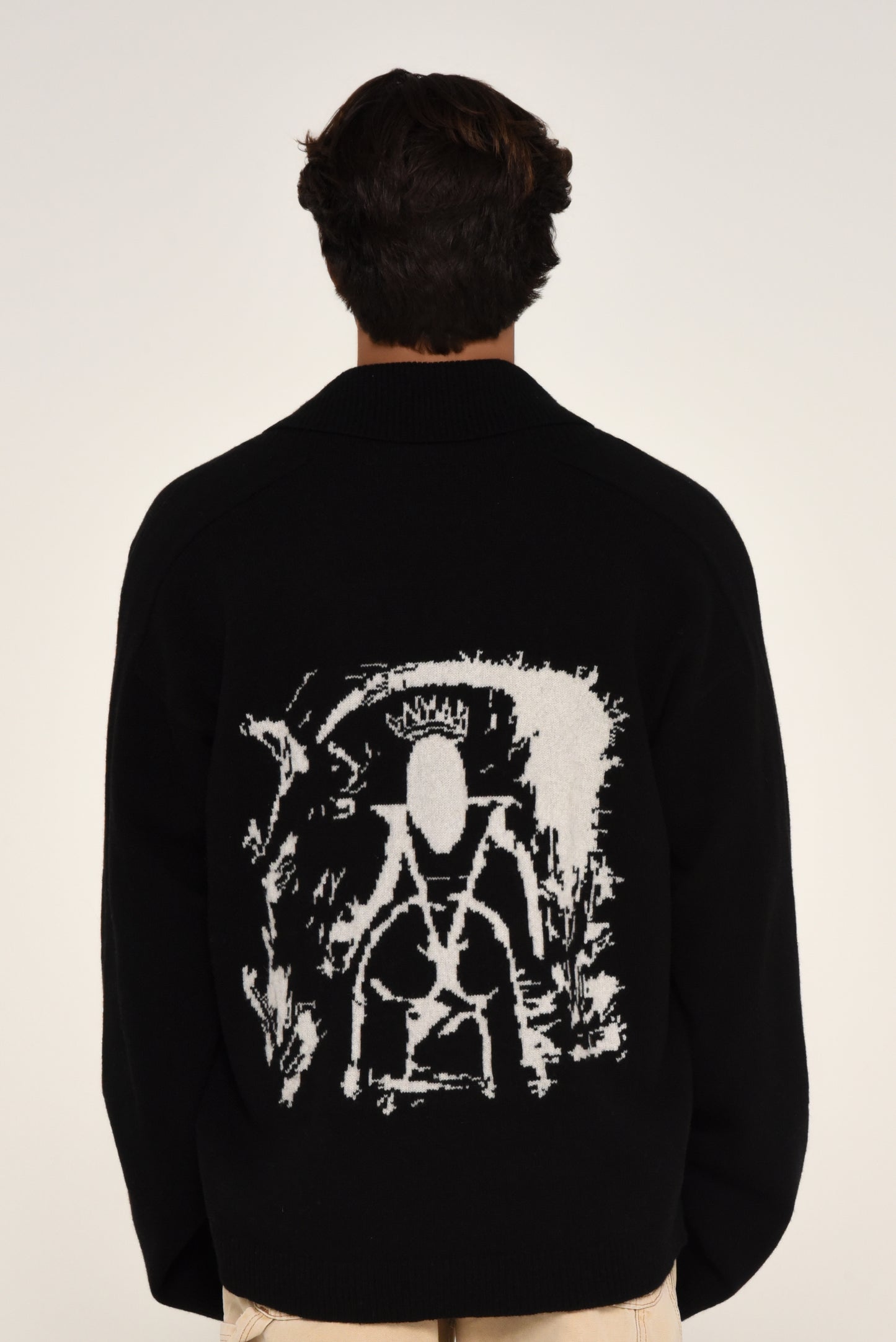 Man wearing a black cardigan with a white graphic design of a woman on the back 