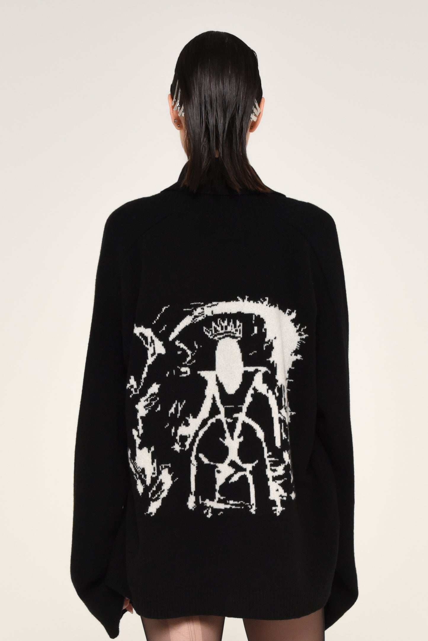 Back view of woman wearing a black cardigan with a white graphic design of a woman on the back 