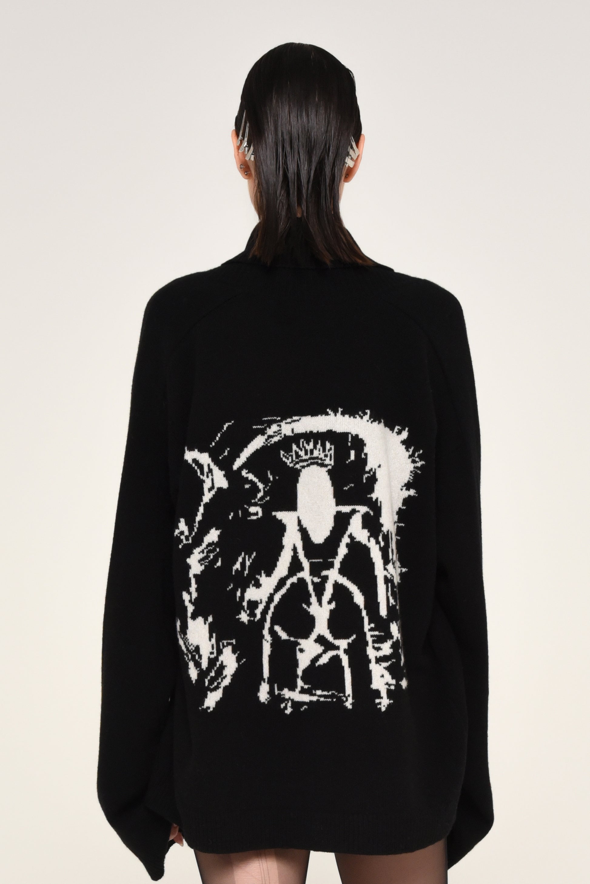 Back view of woman wearing a black cardigan with a white graphic design of a woman on the back 