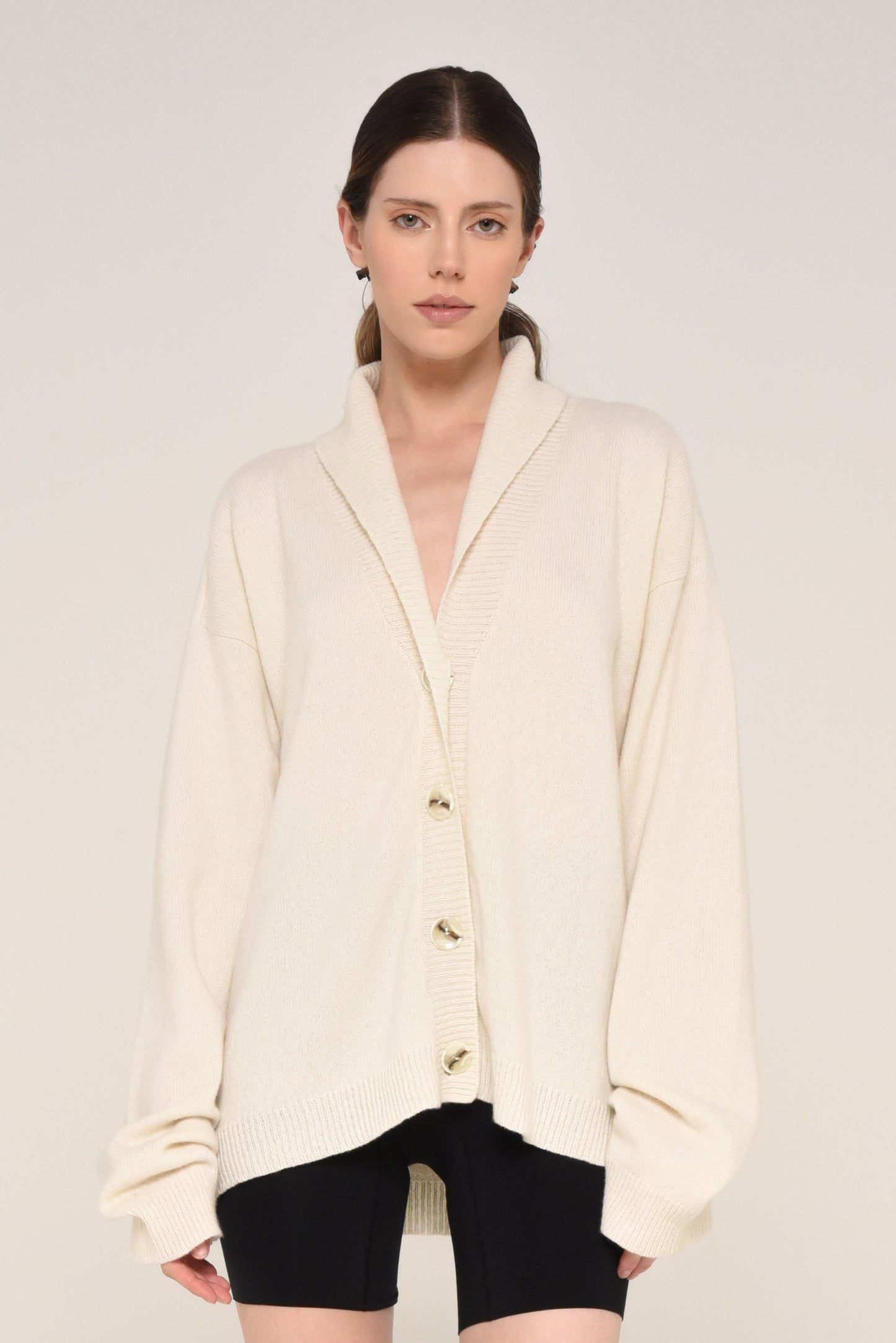 Woman wearing an oversized cream cardigan with buttons