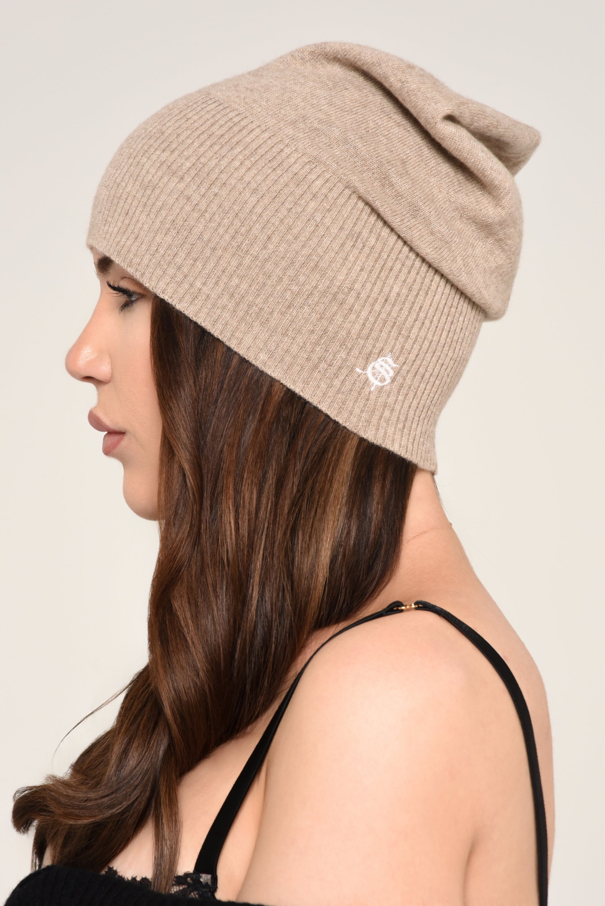 Side view of woman wearing a slouchy beige knit beanie with embroidery 