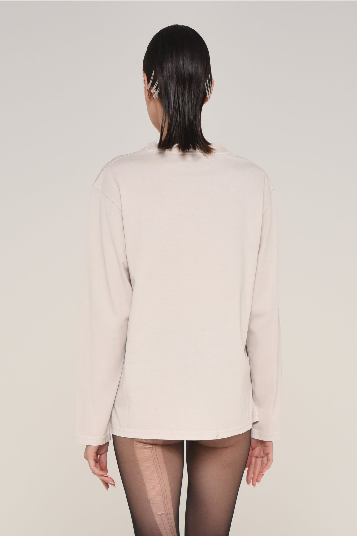 back view of woman wearing an off-white long sleeve shirt and ripped tights