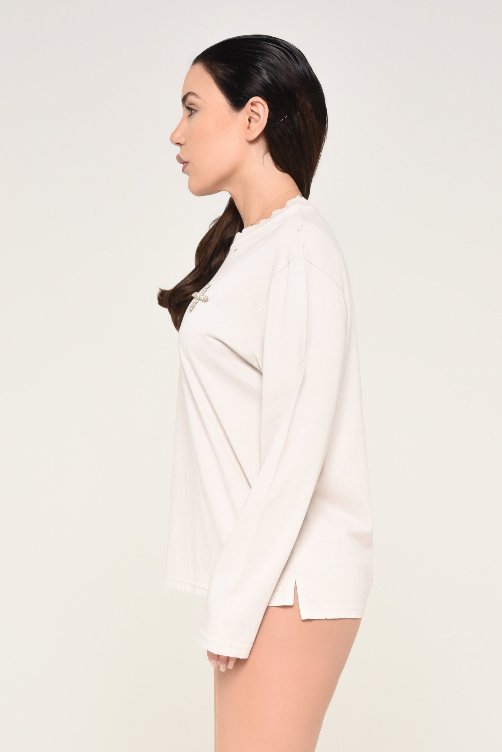side view of woman wearing an off-white long sleeve shirt and ripped tights