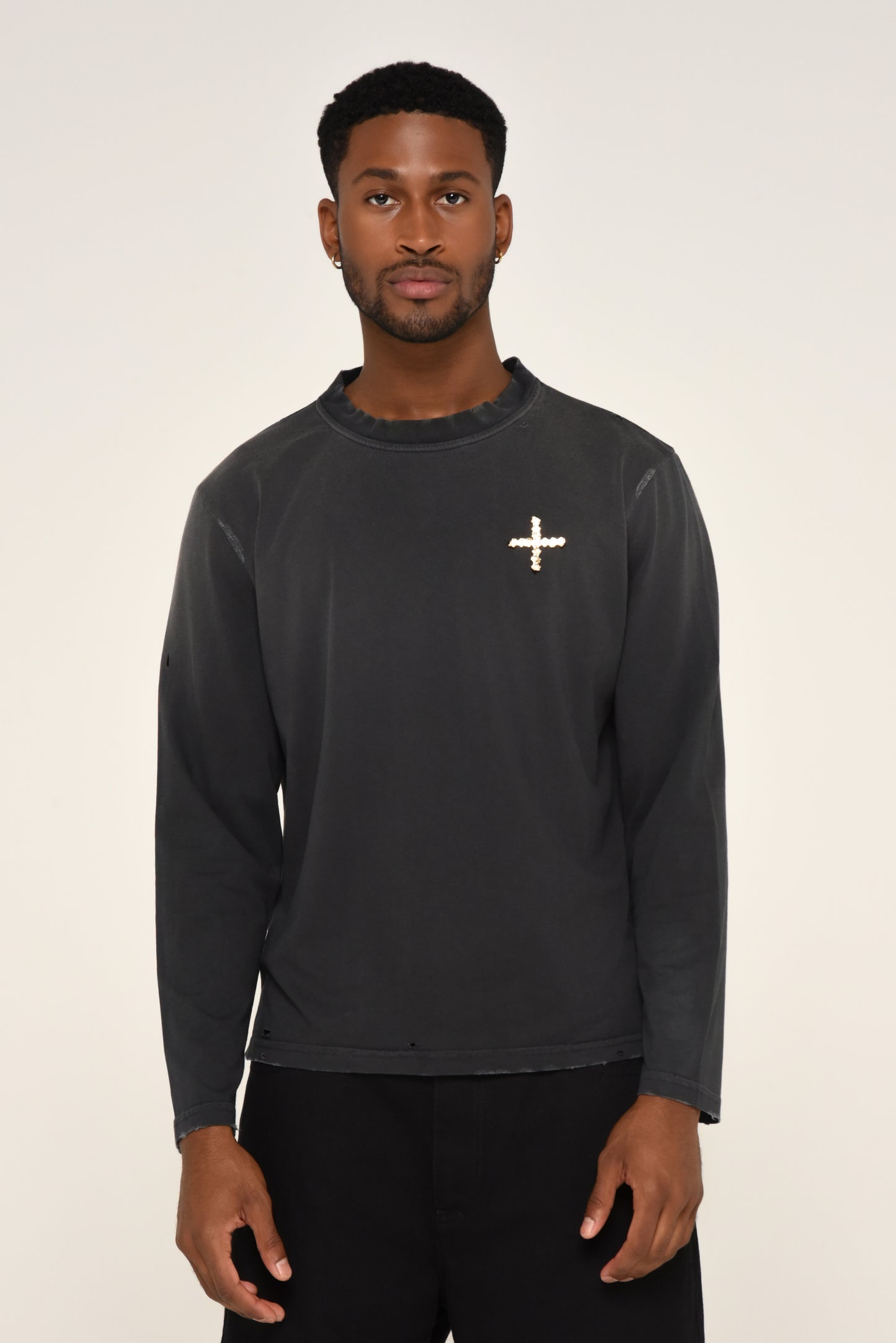 Man wearing a black long sleeve shirt with embroidered cross logo