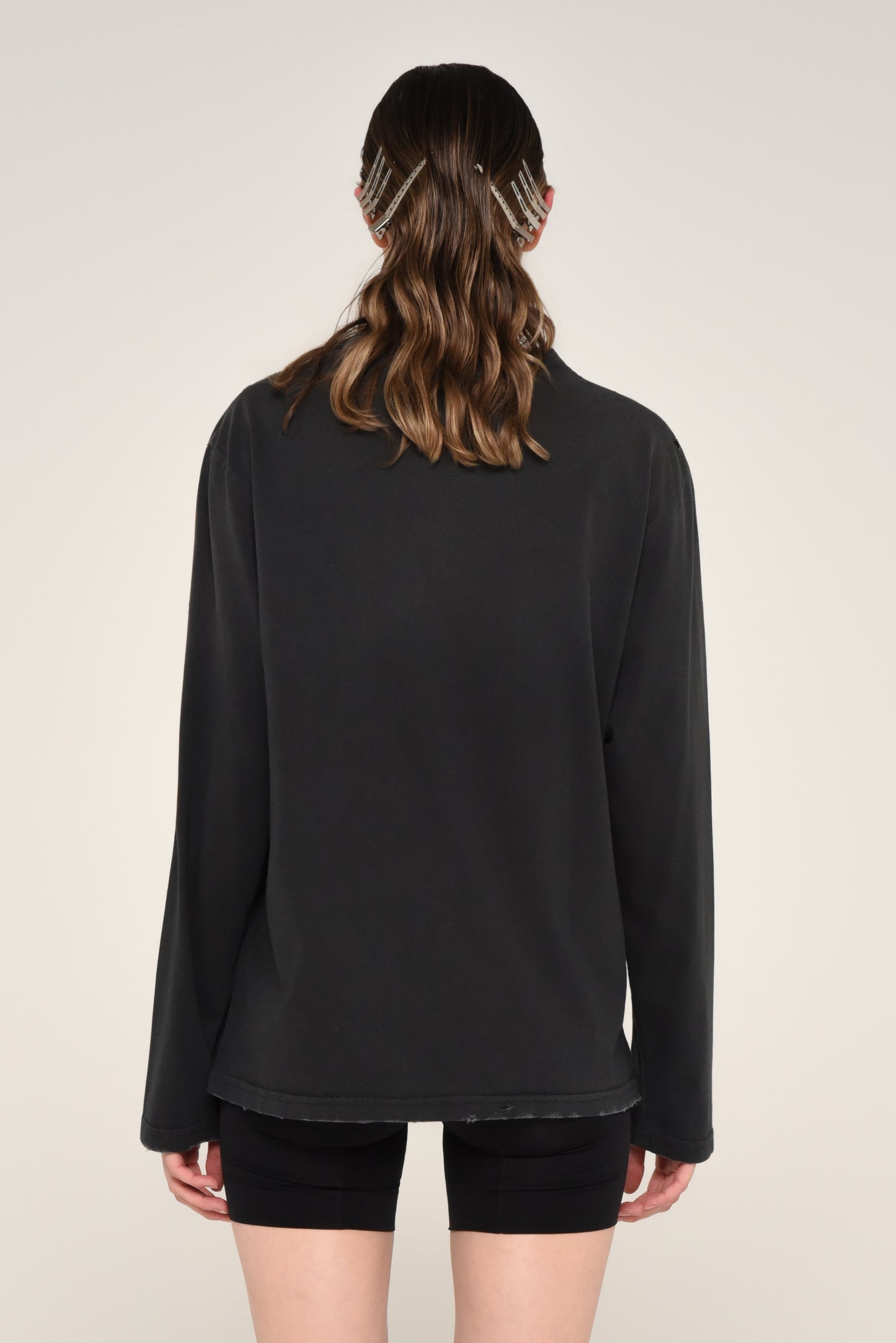 Back view of woman wearing a black long sleeve shirt and biker shorts