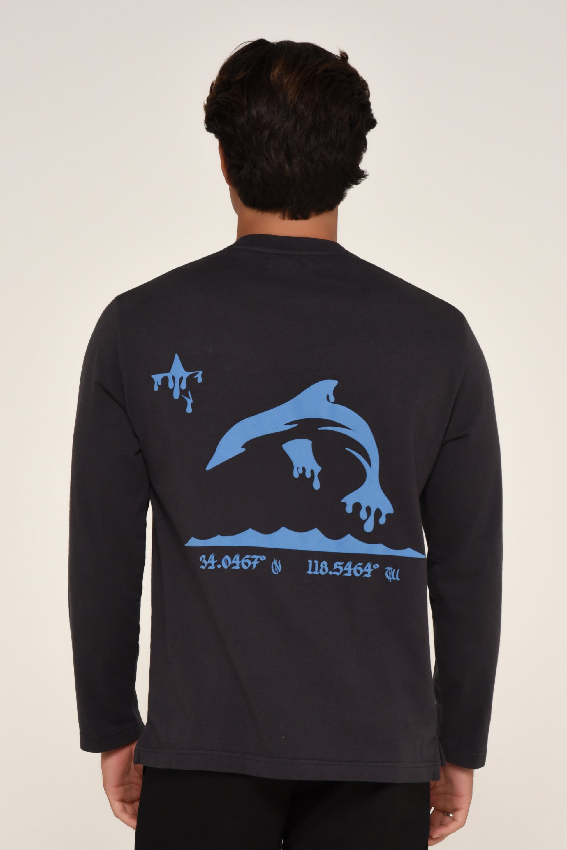 black long-sleeve shirt with blue dolphin graphic and coordinates on a beige background