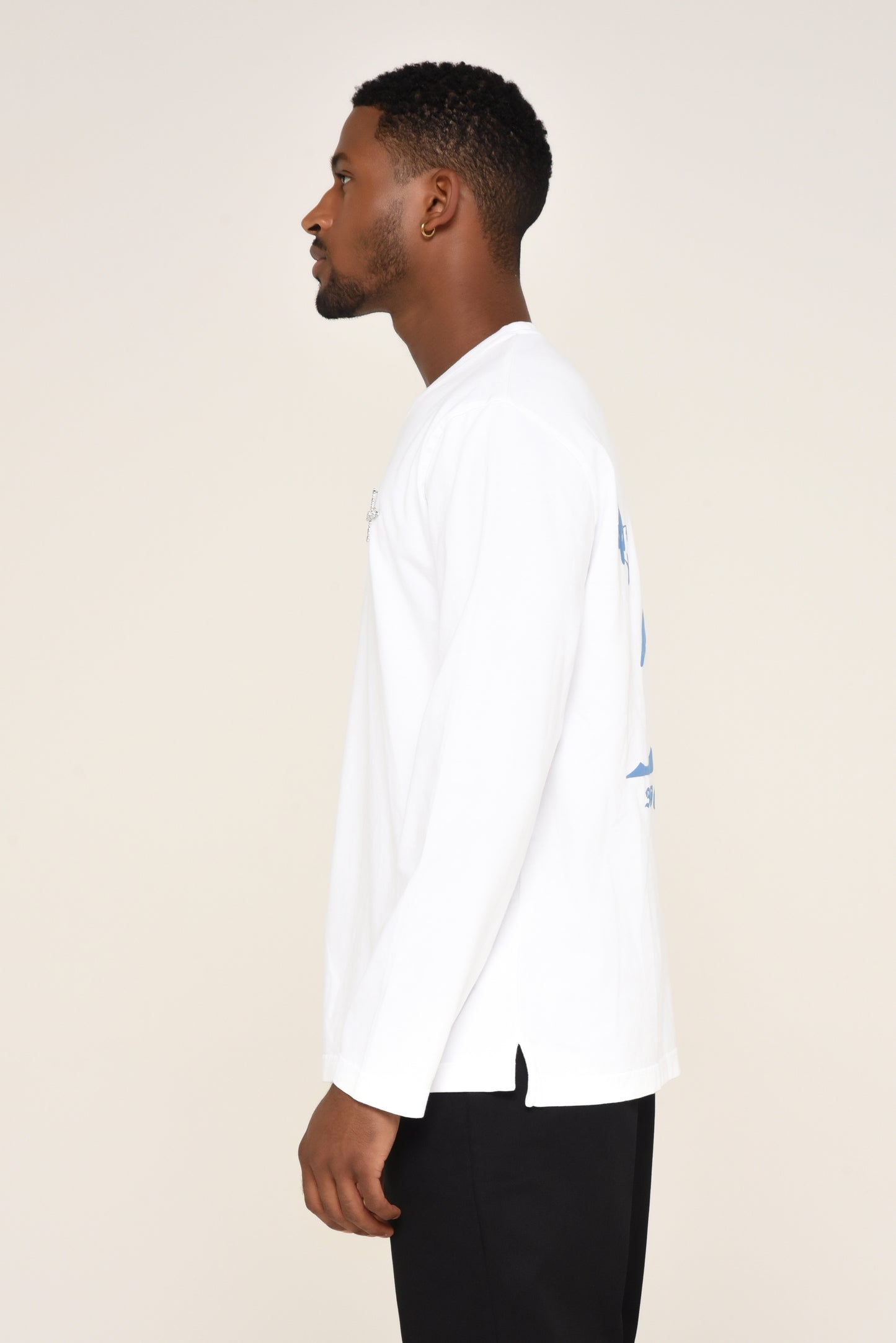 Side view of man wearing a white long-sleeve shirt with cross detail  and red text