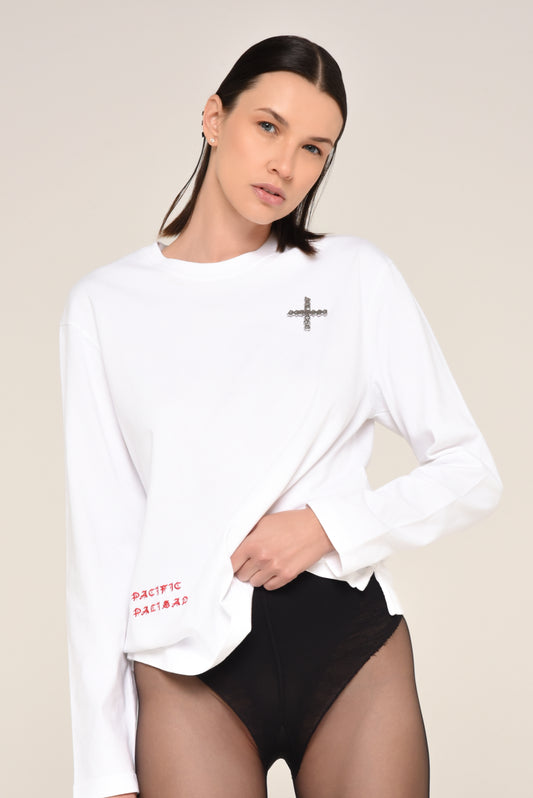 Woman wearing a white long-sleeve shirt with cross detail  and red text