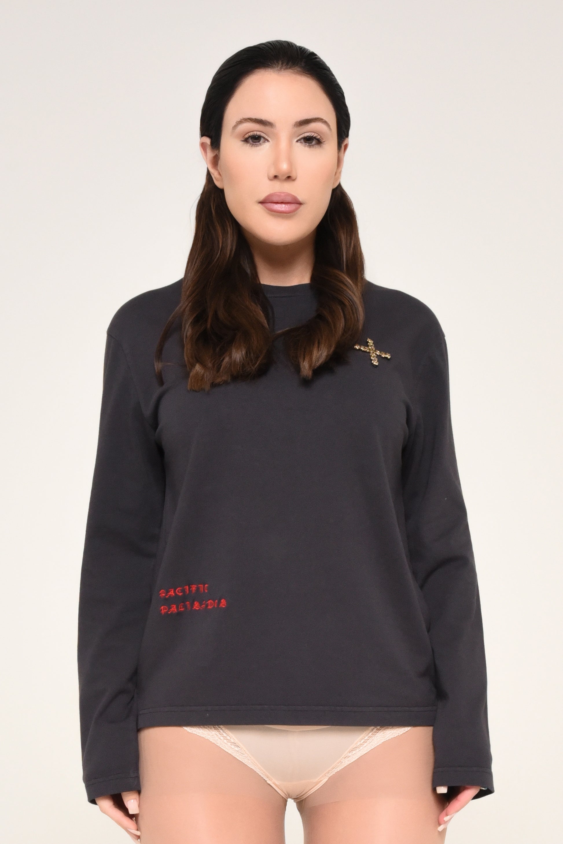 Woman wearing a black long-sleeve shirt with cross detail and red text